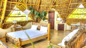 A rustic room with a wooden bed, a small desk, and a chair. - VILLA FUKU - Four Bedroom Villa, Sleeps 10 (Zanzibar)