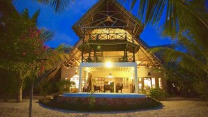 A beachside resort with a thatched-roof structure, a pool, and palm trees. - VILLA FUKU - Four Bedroom Villa, Sleeps 10 (Zanzibar)