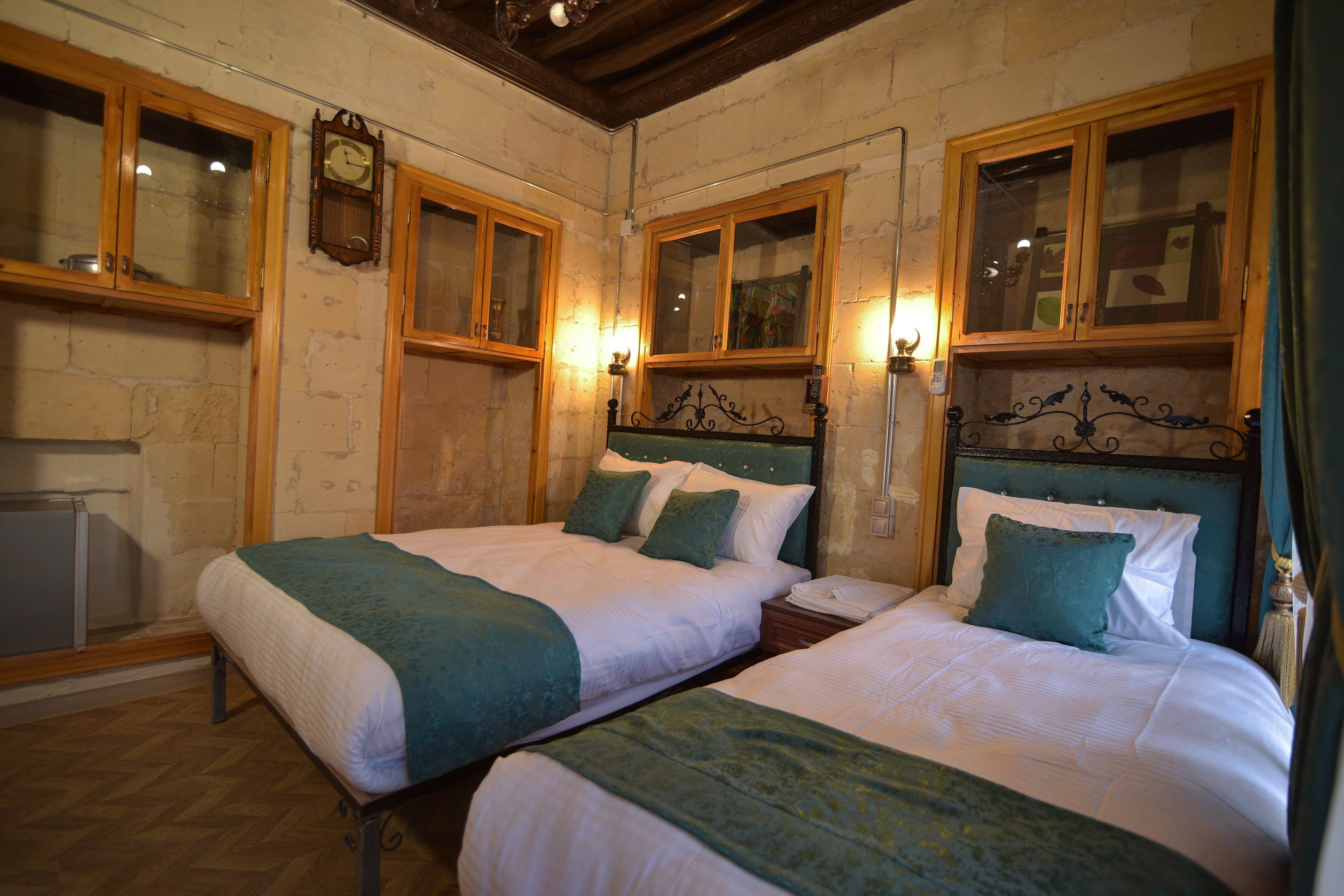 A room with two beds, wooden cabinets, and a clock on the wall.