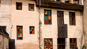 Un patio con un edificio que cuenta con varias ventanas, una escalera y plantas en macetas.