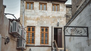 Un patio con un edificio de piedra, una puerta de madera y una escalera que conduce a un nivel superior.