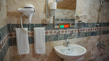 A bathroom with a hairdryer, towel rack, sink, and shower.