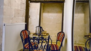 Una habitación con una mesa redonda, cuatro sillas, un radiador y un espejo.
