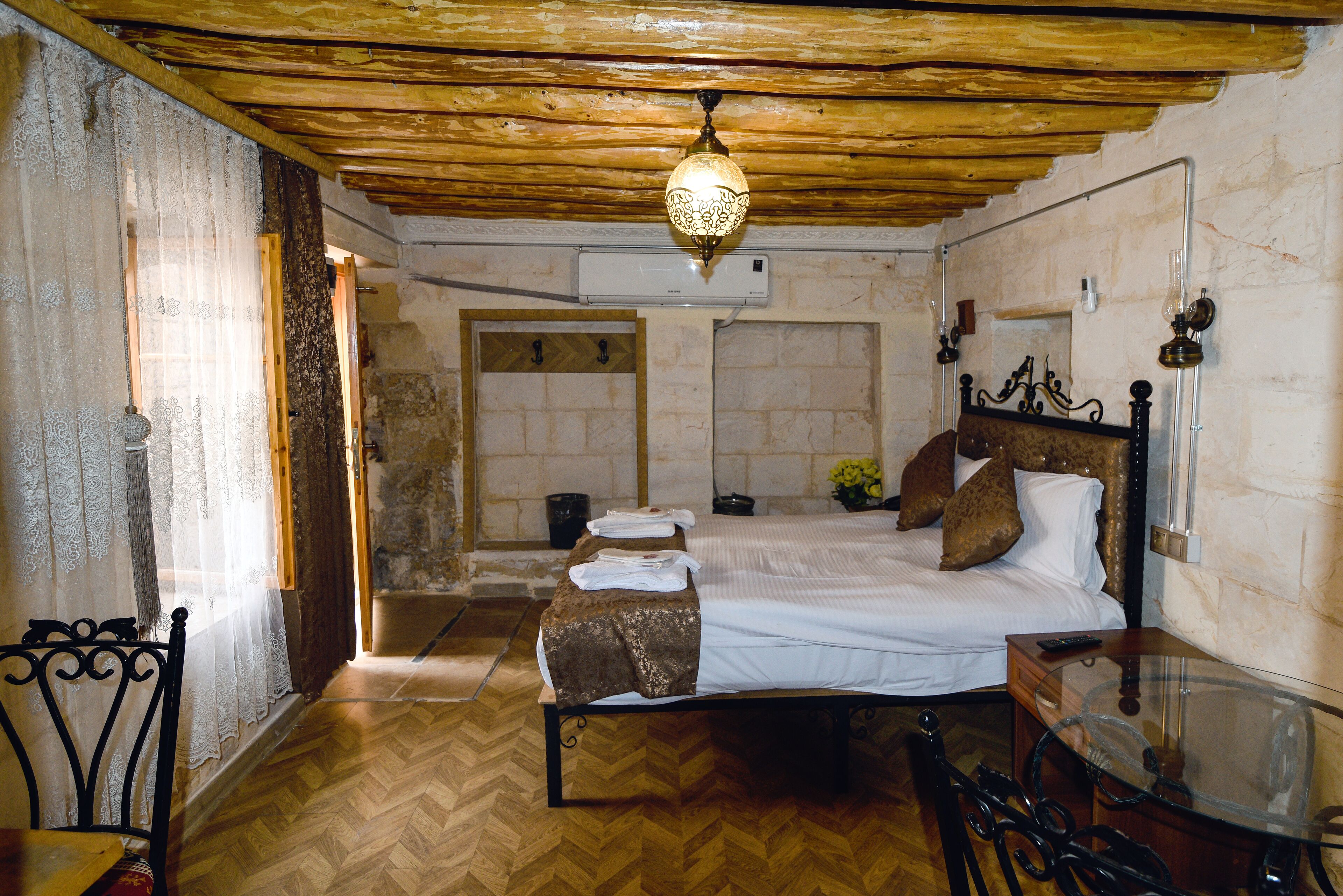 Ein Schlafzimmer mit Holzboden, einem Bett mit weißen Leinen, einer Bank und einem Glastisch.