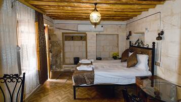 Ein Schlafzimmer mit Holzboden, einem Bett mit weißen Leinen, einer Bank und einem Glastisch.