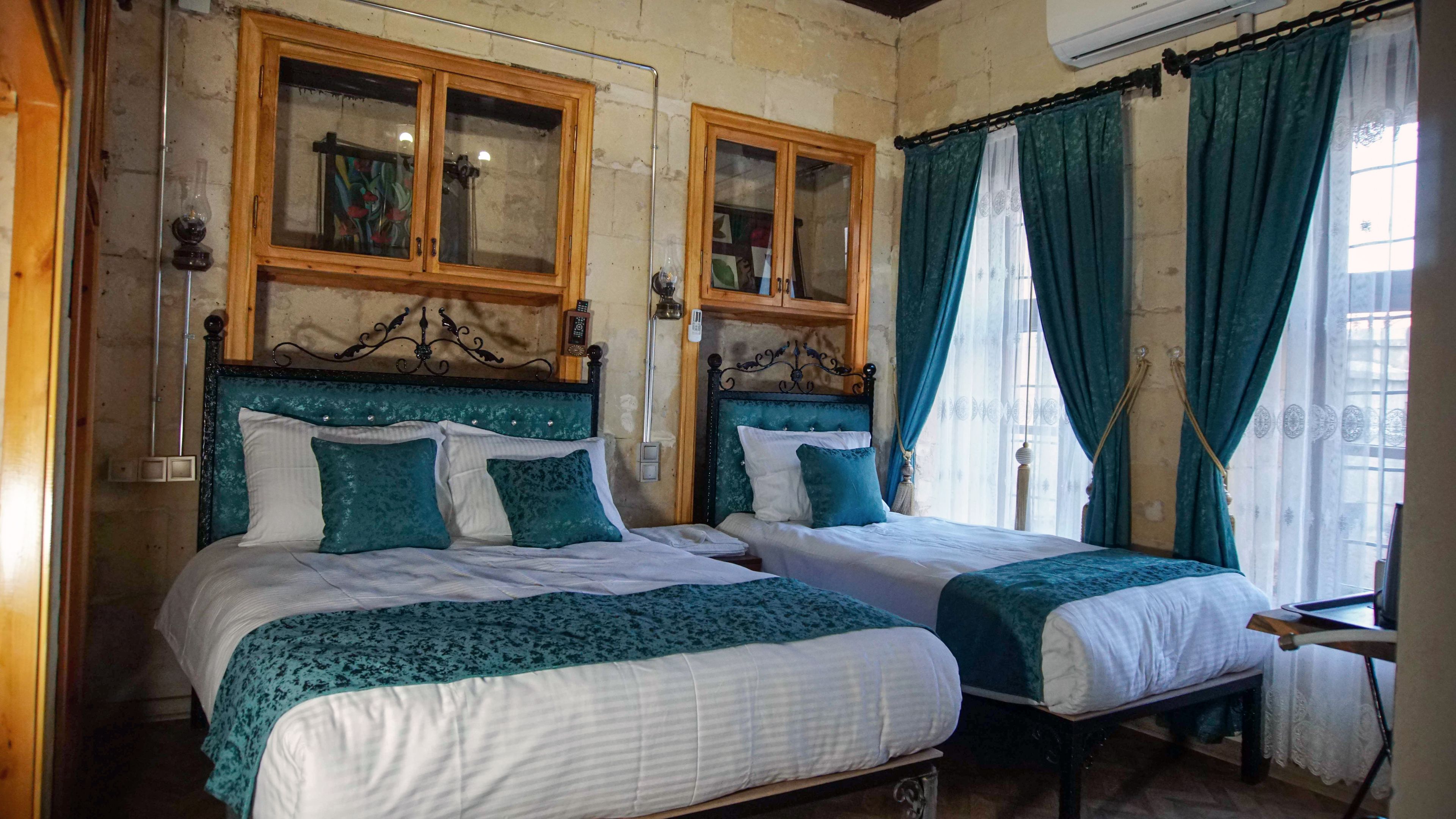 Une chambre avec deux lits, des têtes de lit en bois et une fenêtre avec des rideaux.