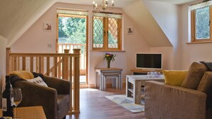 Un salon chaleureux avec un escalier en bois, un téléviseur et un coin repas.