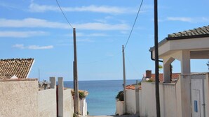 Eine schmale Gasse, die zum Meer führt, mit Häusern an beiden Seiten.