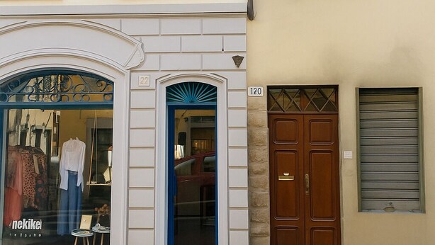 Un edificio con una tienda en la planta baja, que presenta una entrada azul y un maniquí en la ventana.