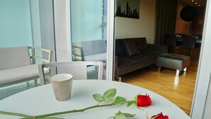 Una sala de estar moderna con una mesa blanca, un sofá, una mesa de centro y una rosa sobre la mesa.