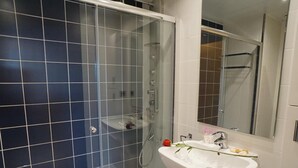 Un baño moderno con ducha envuelta en vidrio, un lavamanos blanco y un espejo sobre él.