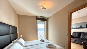 Habitación de hotel con dos camas, un balcón y vistas a la ciudad.