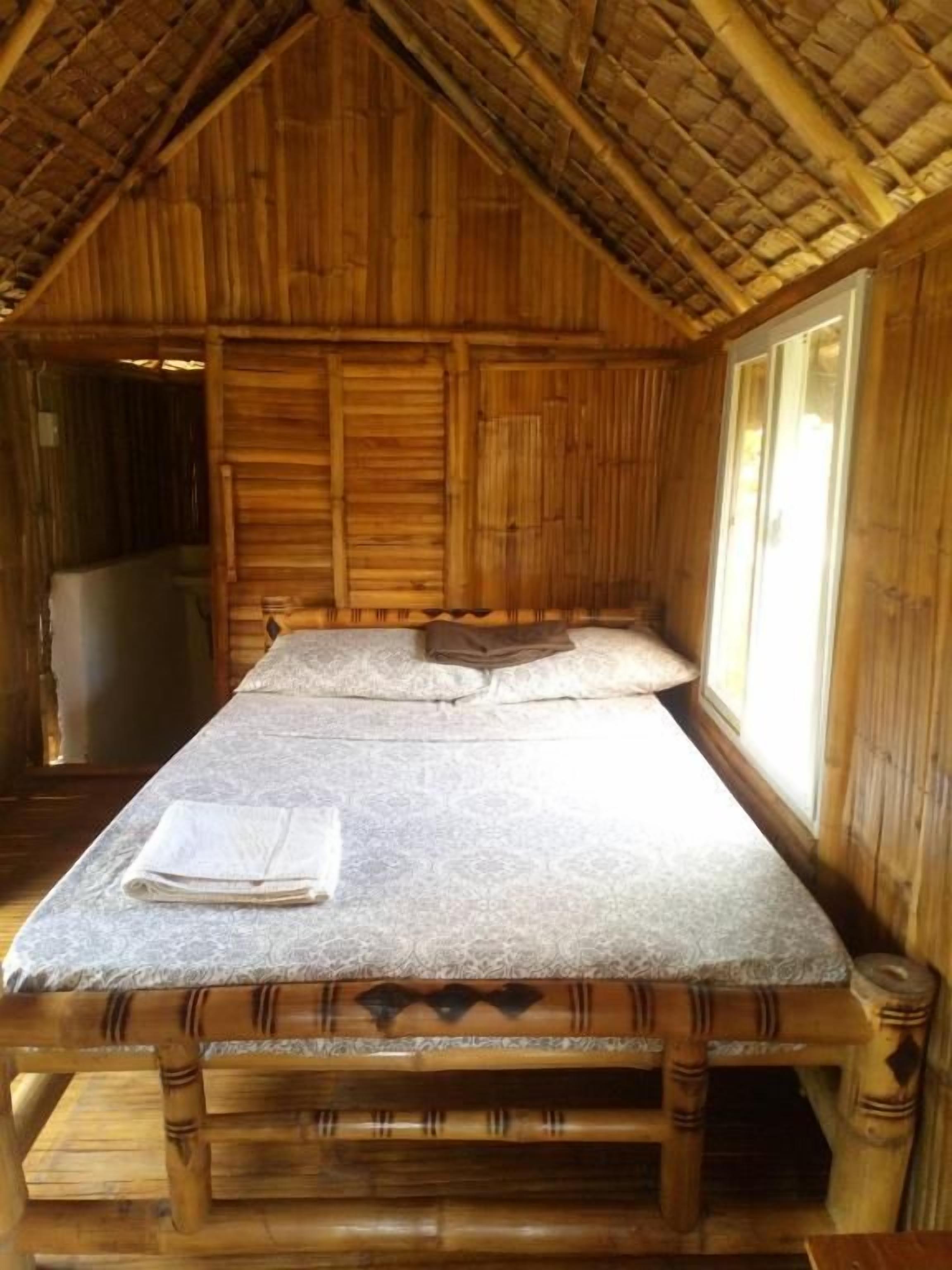 Una habitación de madera con una cama, una ventana y una puerta.