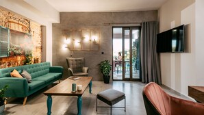 A modern living room with a teal sofa, a wooden coffee table, and a brown leather armchair. - Views, Pool, Garden, BBQ, Playground, Tennis Table (CHANIA)