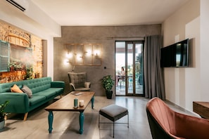 Relax in this stylish living room with a sofa, armchair, and large flat-screen TV, plus a sliding door to an outdoor space with a view.