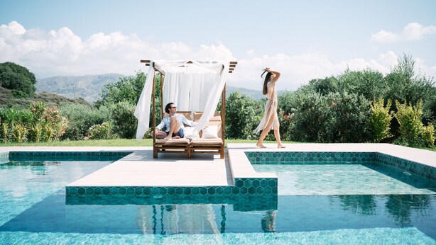 A poolside area with a canopy bed, a lounge chair, and a person walking. - Views, Pool, Garden, BBQ, Playground, Tennis Table (CHANIA)