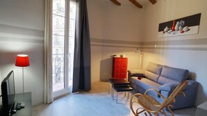 A modern living room with a sofa, a rocking chair, a red storage unit, and a painting on the wall. - Chic studio in a perfect location in Barcelona (Barcelona)