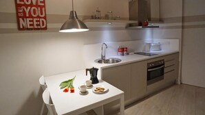 A modern kitchen with a white table, a coffee maker, and a sign that reads "LOVE YOU NEED". - Chic studio in a perfect location in Barcelona (Barcelona)