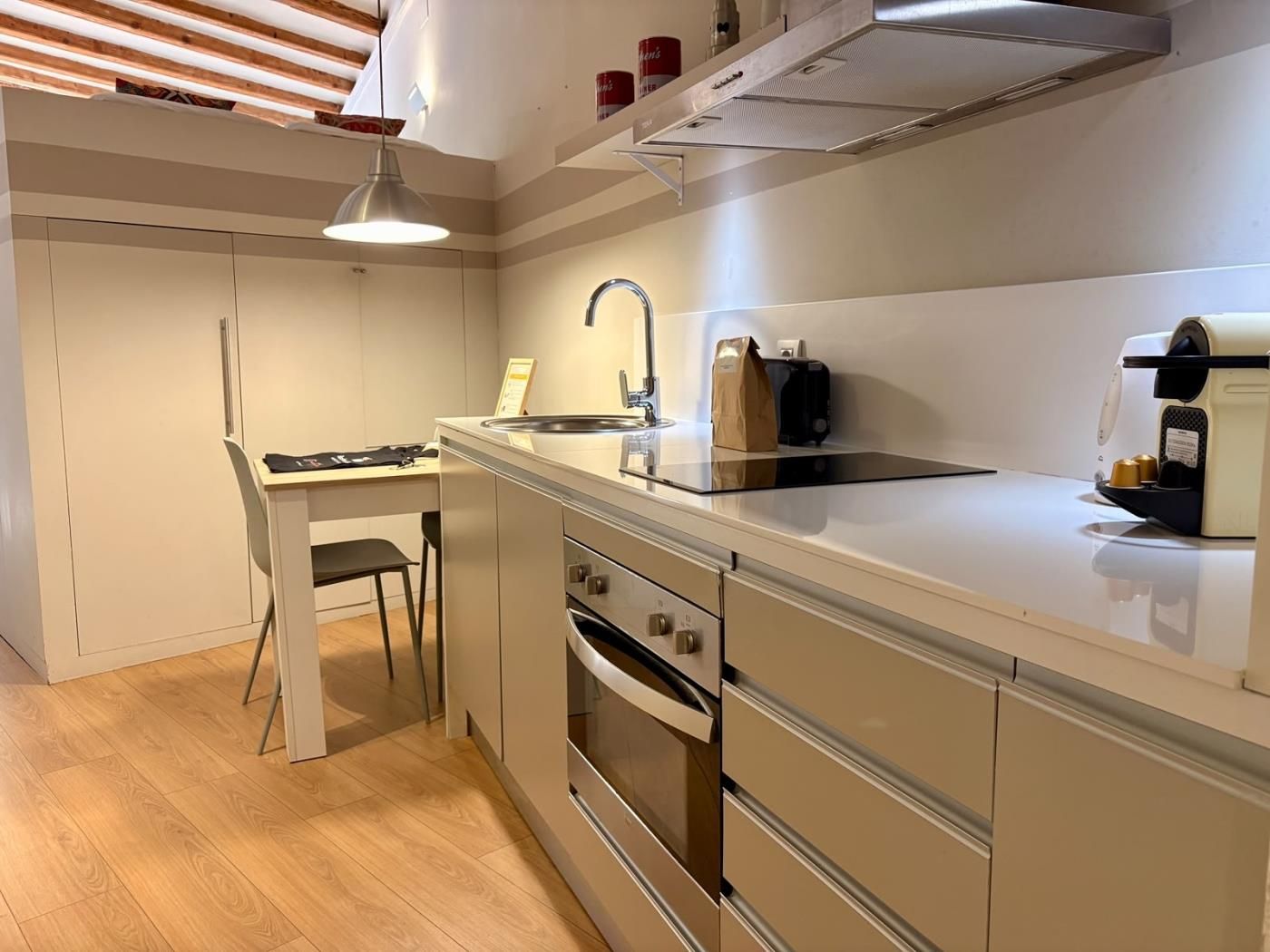 Een moderne keuken met een ingebouwde oven, een spoelbak en een koffieapparaat.