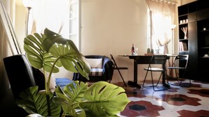 A living room with a large green plant, a black chair, a dining table with chairs, and a bookshelf. - santamarta35: characteristic apartment in a great location (Pisa)