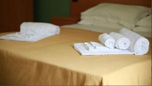 A bed with a beige bedspread, two rolled towels, and a white pillow. - Residence Medimare ~ TWO-ROOM APARTMENT 14 (Patti Sicilia)