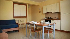 A compact living space with a dining area, kitchenette, and a sofa. - Residence Medimare ~ TWO-ROOM APARTMENT 14 (Patti Sicilia)