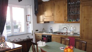 A kitchen with wooden cabinets, a stove, and a sink. There is a dining table with chairs and a fruit basket. - Apartment with 2 bedrooms and kitchen (Avezzano)