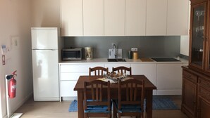 A compact kitchen with white cabinets, a microwave, a coffee maker, and a sink. There is a wooden dining table with chairs and a fire extinguisher on the wall. - House of Quinteiro de Azagães (Azagães)