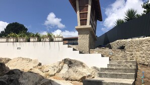 A stone staircase leading up to a wooden structure with a tiled roof, surrounded by a white wall and potted plants. - House of Quinteiro de Azagães (Azagães)