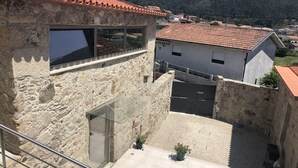 A stone building with a tiled roof, a large window, and a gated entrance. - House of Quinteiro de Azagães (Azagães)