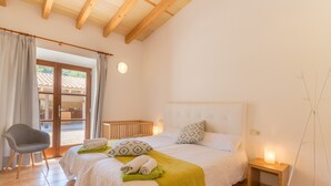 Une chambre avec un grand lit, deux tables de chevet, une chaise et une vue sur l’extérieur, visible à travers une porte vitrée.