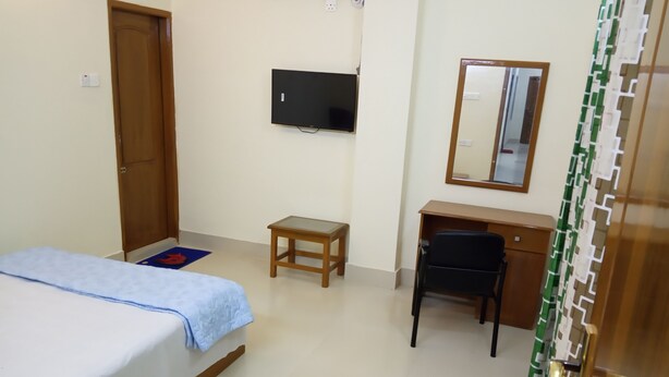 Una camera da letto con un letto, una scrivania, una sedia, una televisione e uno specchio.