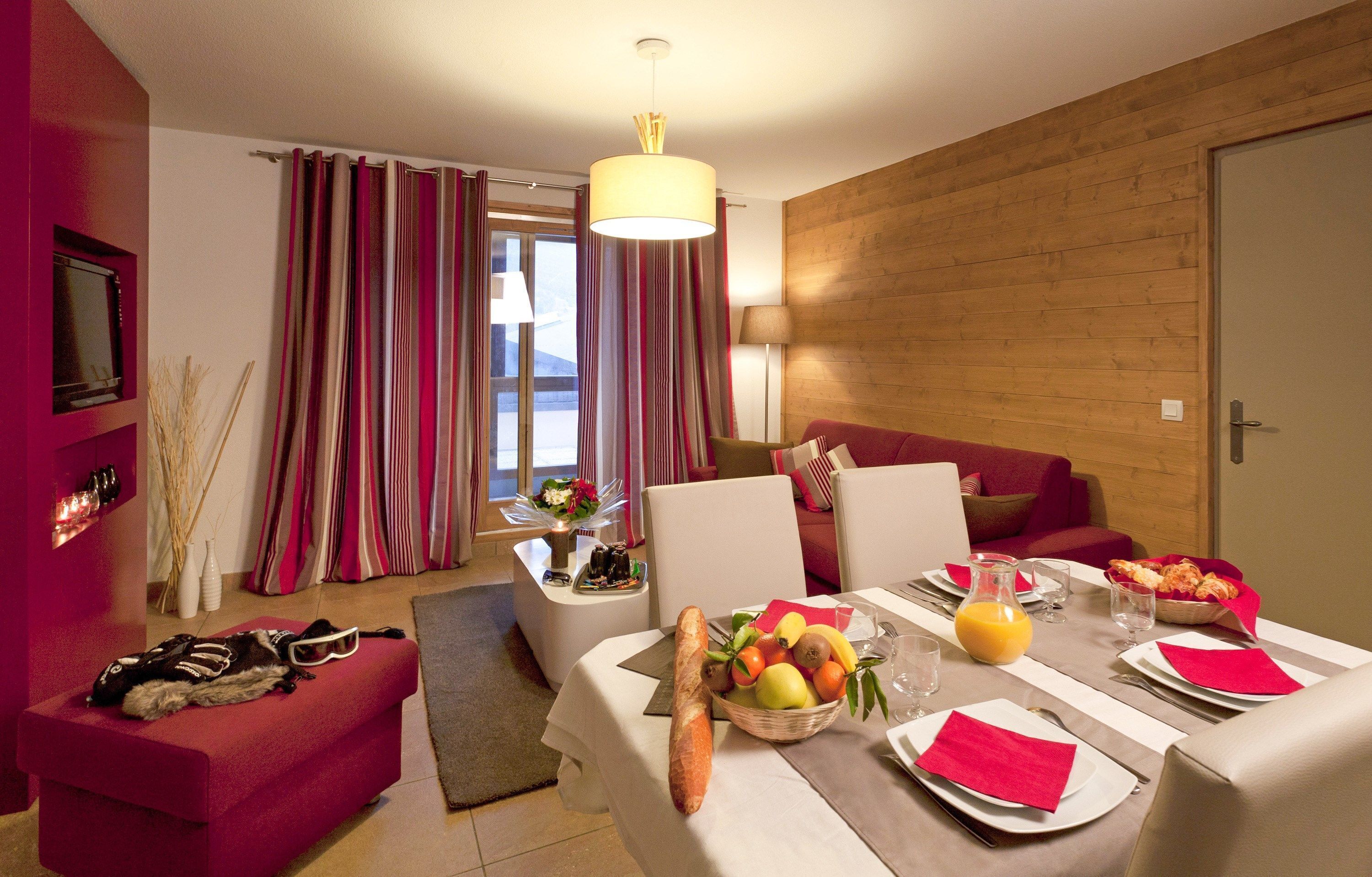 A modern dining area with a table set for breakfast, including bread, fruits, and juice.