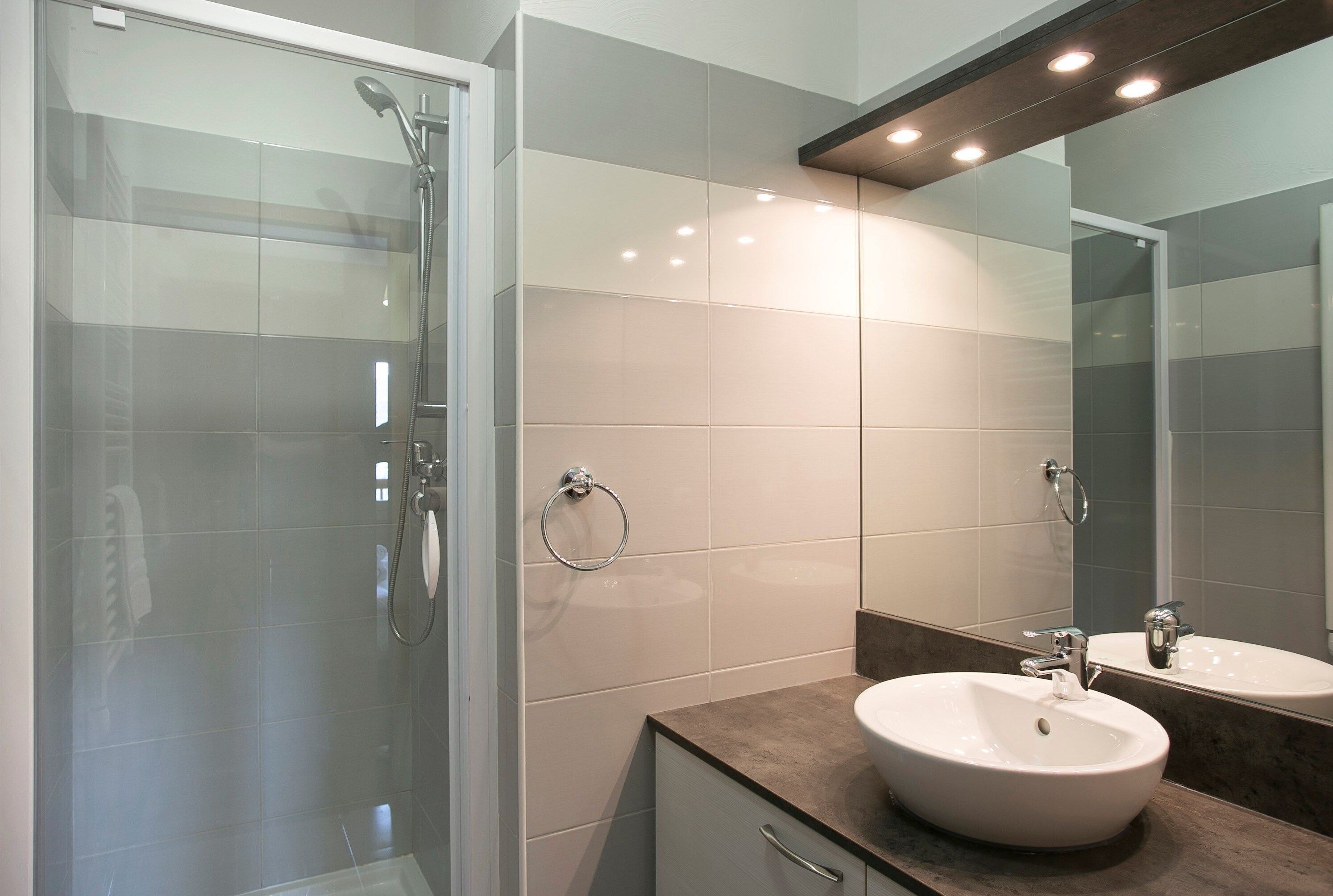 A modern bathroom with a glass-enclosed shower, a sink, and a mirror.