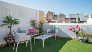 A rooftop terrace with a white sofa, two chairs, a small table, and potted plants. - Albareda 6 - Two Bedroom Apartment, Sleeps 4 (Sevilla)