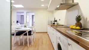 A modern kitchen with a washing machine, a dining area with a table and chairs, and a view into a bedroom. - Albareda 6 - Two Bedroom Apartment, Sleeps 4 (Sevilla)