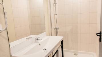 A bathroom with a white sink, mirror, and shower.