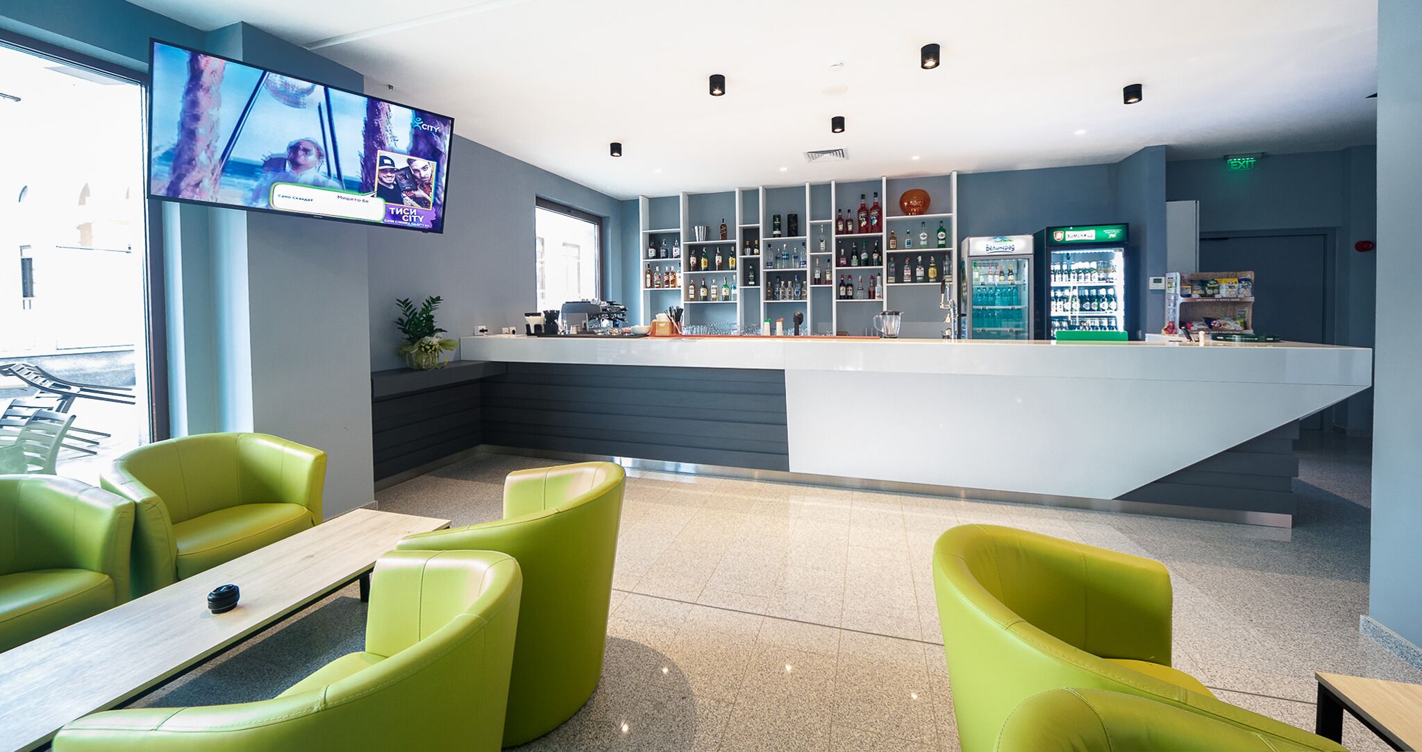 A modern bar area with a counter, seating, and a television screen.