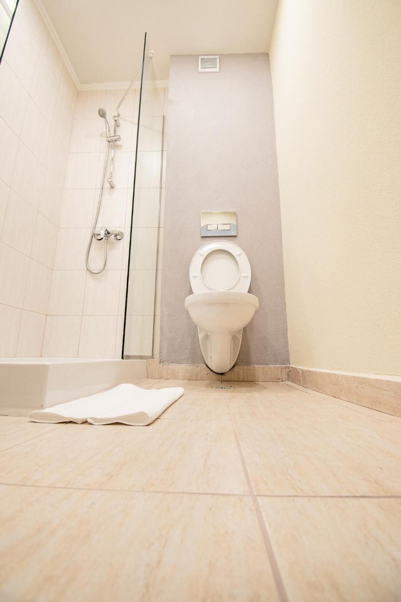 Un baño con inodoro, ducha y una toalla en el suelo.