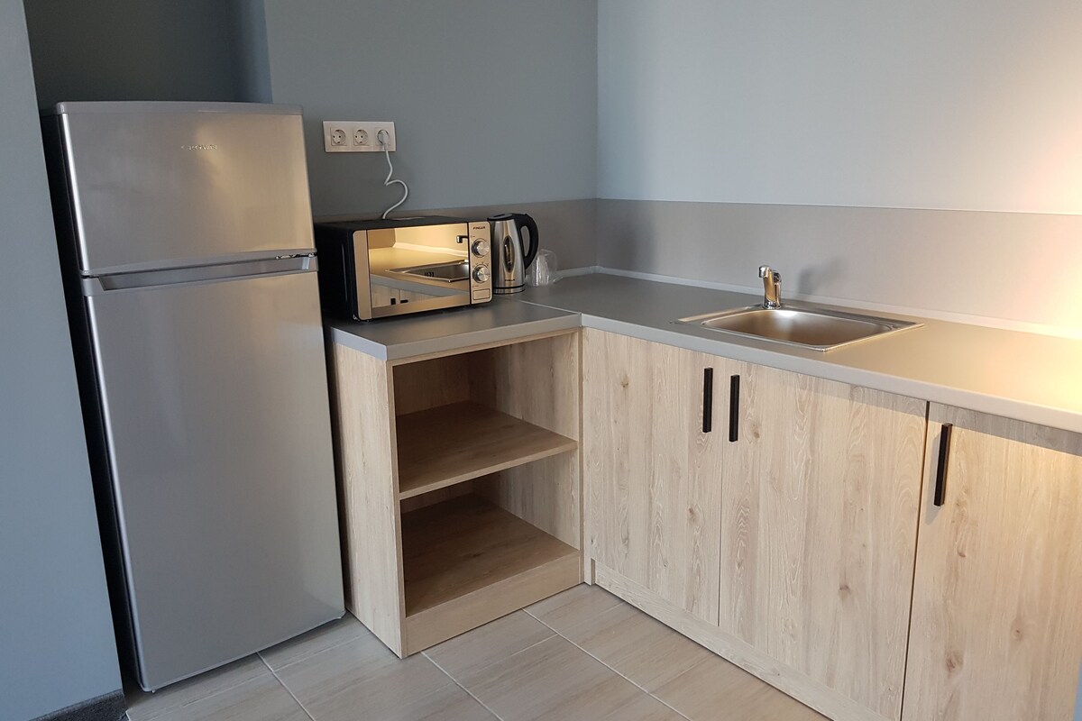 Una cocina compacta equipada con un refrigerador, tostadora y pileta.