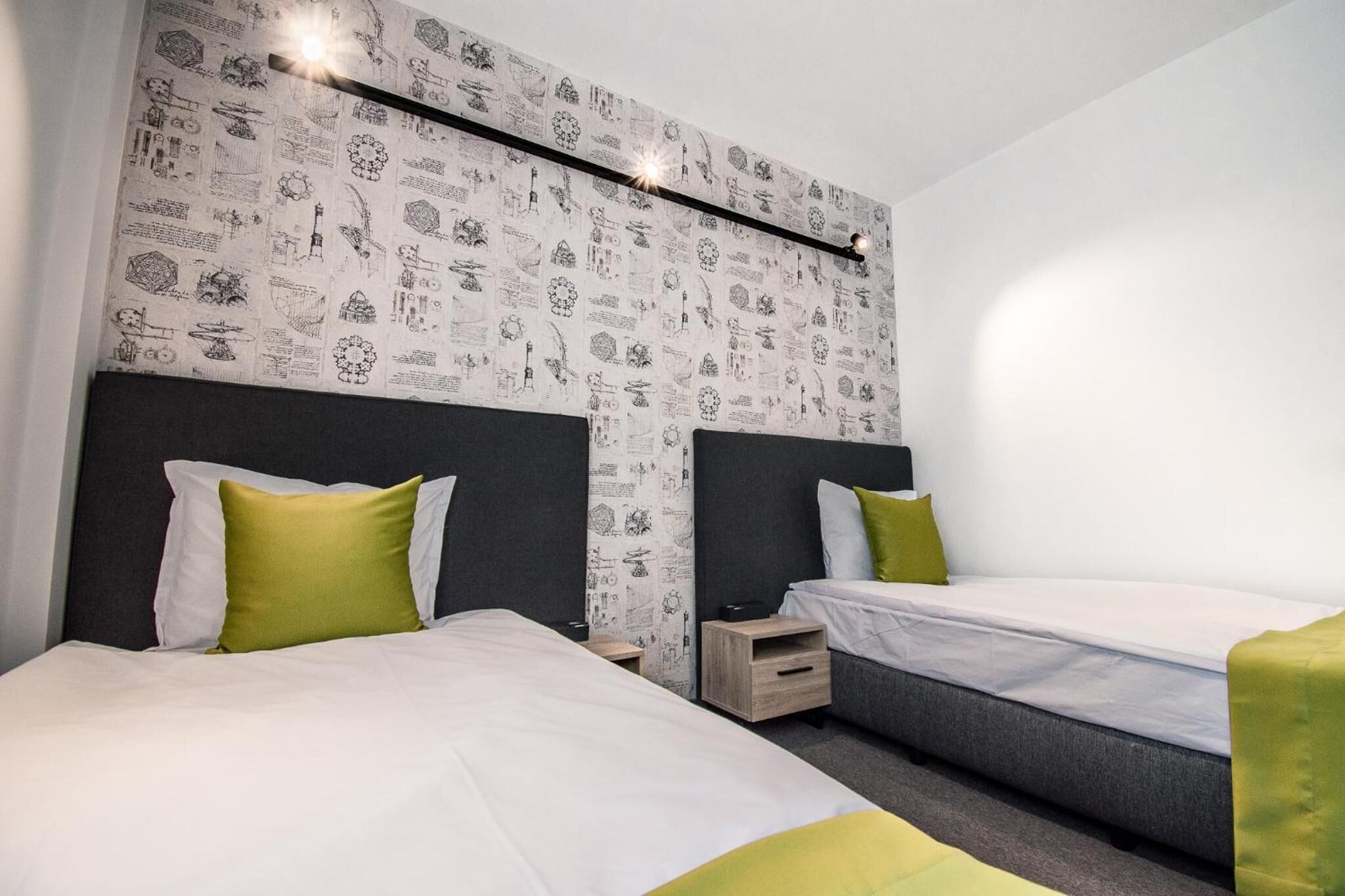 A hotel room with two beds, a patterned wallpaper, and a modern light fixture.