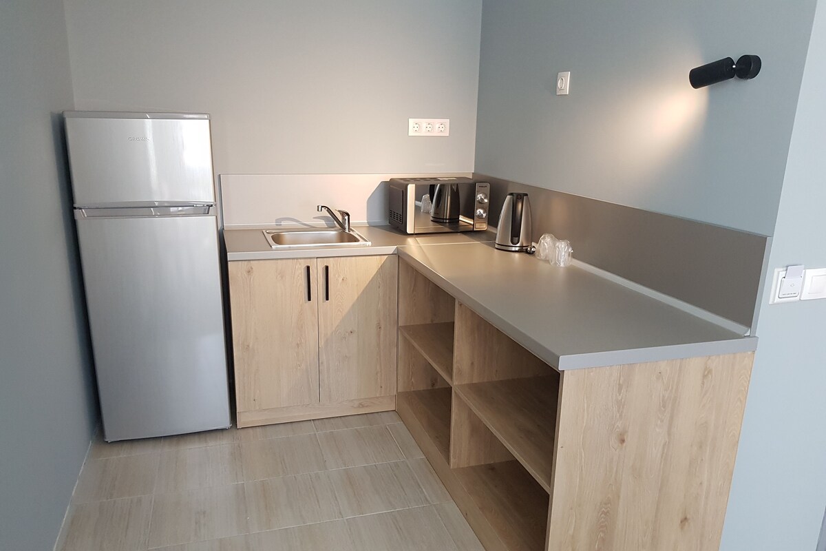A compact kitchen with a refrigerator, sink, and wooden cabinets.