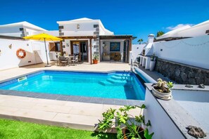 Une maison moderne dotée d’une piscine, de mobilier d’extérieur et d’un espace patio.
