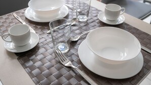 A table set with white plates, bowls, cups, and a glass.