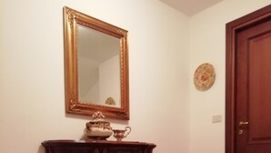 A hallway with a wooden cabinet, a mirror, and a door. - La via del bosco Apartment in a villa (Casteldelfino)