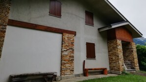 A building with a stone facade, wooden shutters, and a bench outside. - La via del bosco Apartment in a villa (Casteldelfino)