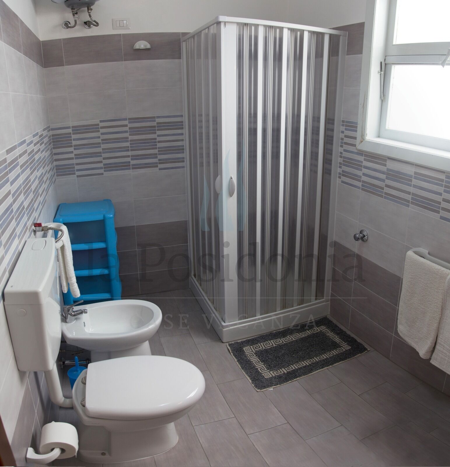 A bathroom with a shower, toilet, and bidet.