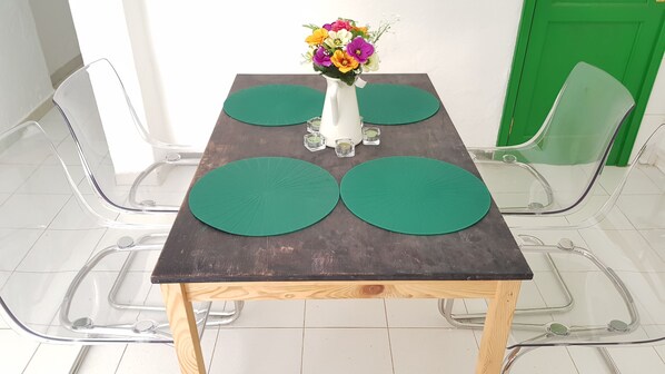 A table with a vase of flowers, two green placemats, and clear glass candle holders. - Saltpeter: 1st Beach Line (Caleta de Famara)