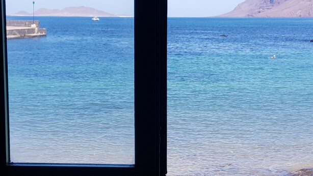 A coastal view with a pier and boats. - Saltpeter: 1st Beach Line (Caleta de Famara)