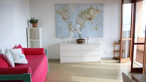 Una habitación con un sofá rojo, un tocador blanco y un mapa mundial en la pared.